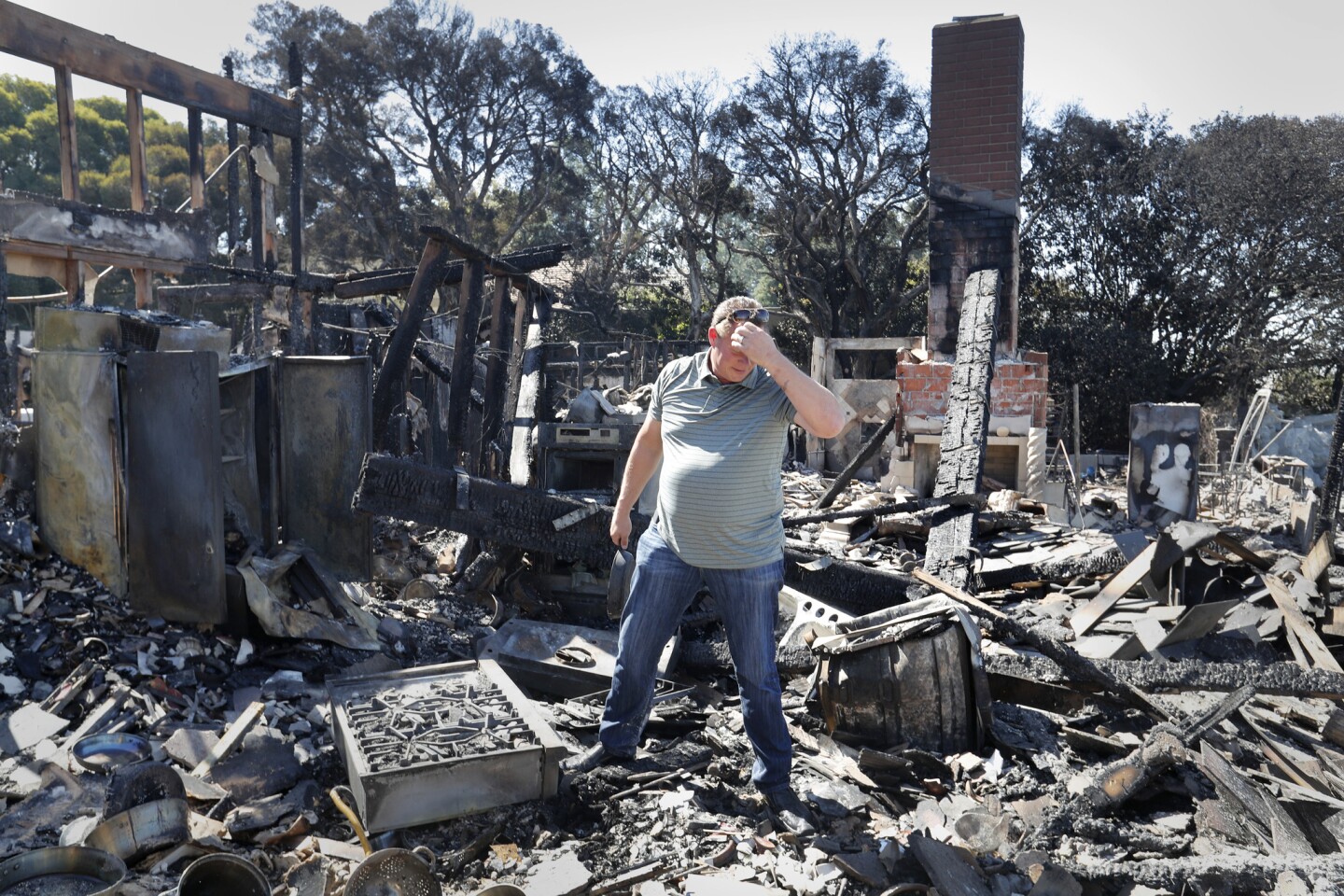 Holding a cast-iron skillet passed down to him from his grandmother, Danny Williamson looks through the remains of his home that was destroyed on Via El Estribo.