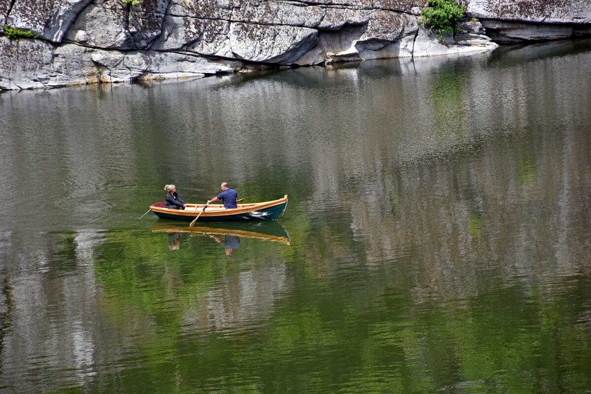 A rower and passenger, in an elegant vessel reminiscent of an Adirondack guide boat, enjoy Lake Mohonk.