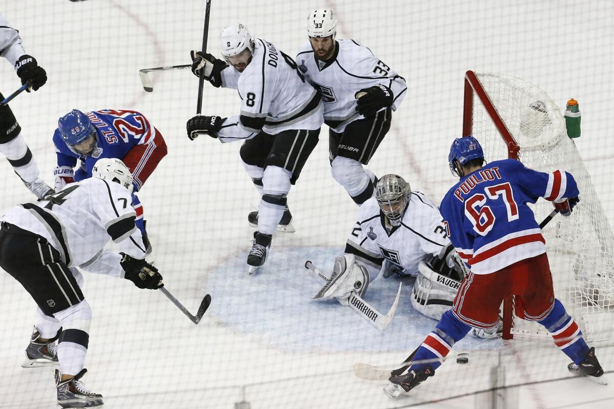 New York Rangers forward Martin St. Louis, right, passes the puck to teammate Benoit Pouliot in front of Kings goalie Jonathan Quick during Game 3 of the Stanley Cup Final.