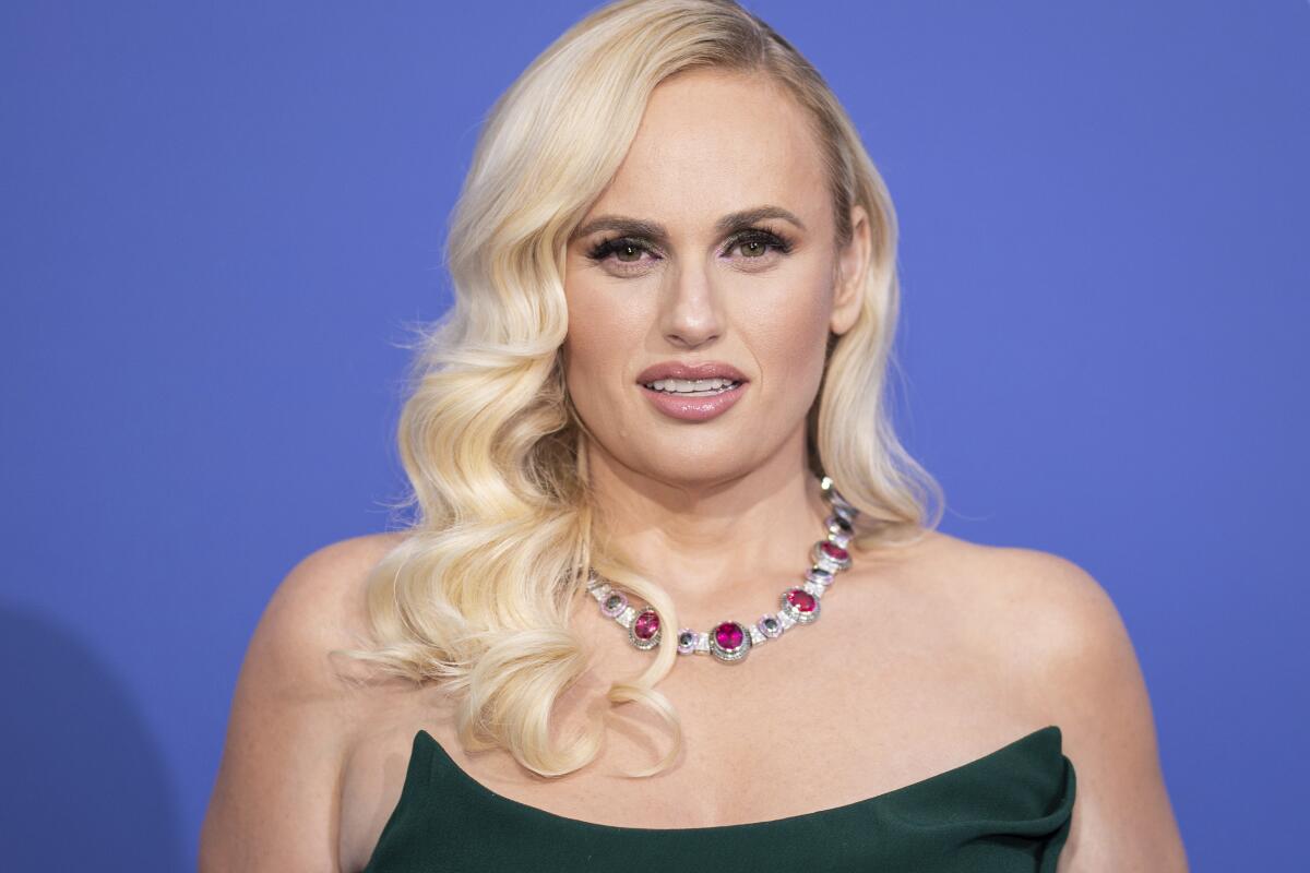 Rebel Wilson with wavy blond hair and a jeweled necklace