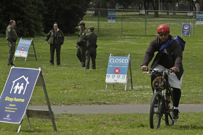 San Francisco Park Rangers guard an entrance that leads to Hippie Hill due to COVID-19 concerns on Monday, April 20, 2020, at Golden Gate Park in San Francisco. People annually gather on April 20, 4/20, to smoke marijuana on Hippie Hill. (AP Photo/Ben Margot)