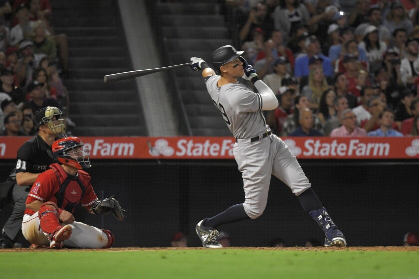 New York Yankees' Aaron Judge hits a solo home run as Angels catcher Matt Thaiss and home plate umpire Quinn Wolcott watch.