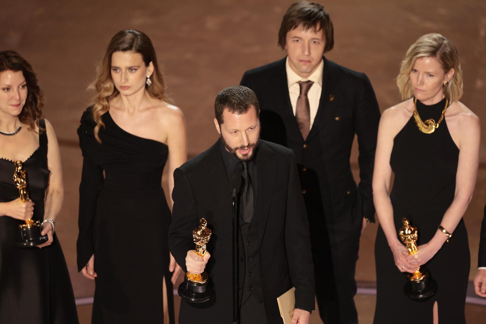'20 Days in Mariupol' director Mstyslav Chernov, center, accepting the Oscar for documentary feature at 96th Academy Awards