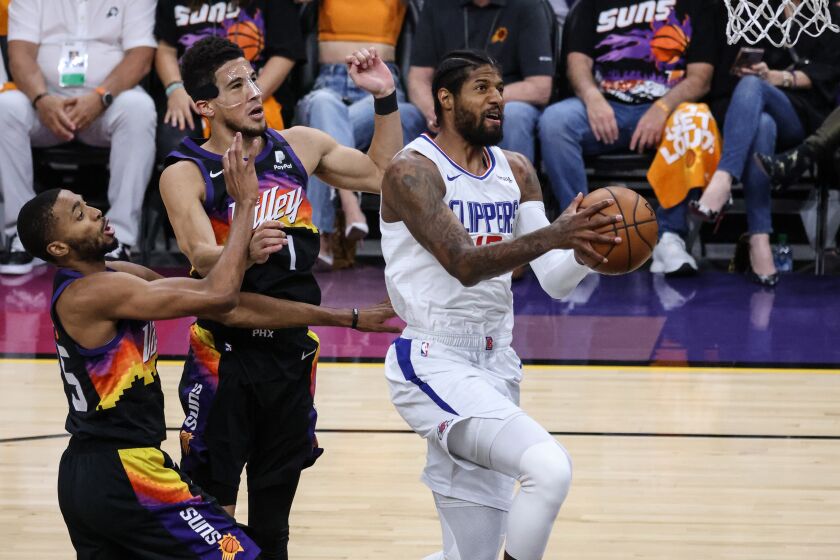 Clippers forward Paul George elevates past Suns guard Devin Booker and forward Mikal Bridges (25) for a layup during Game 5.