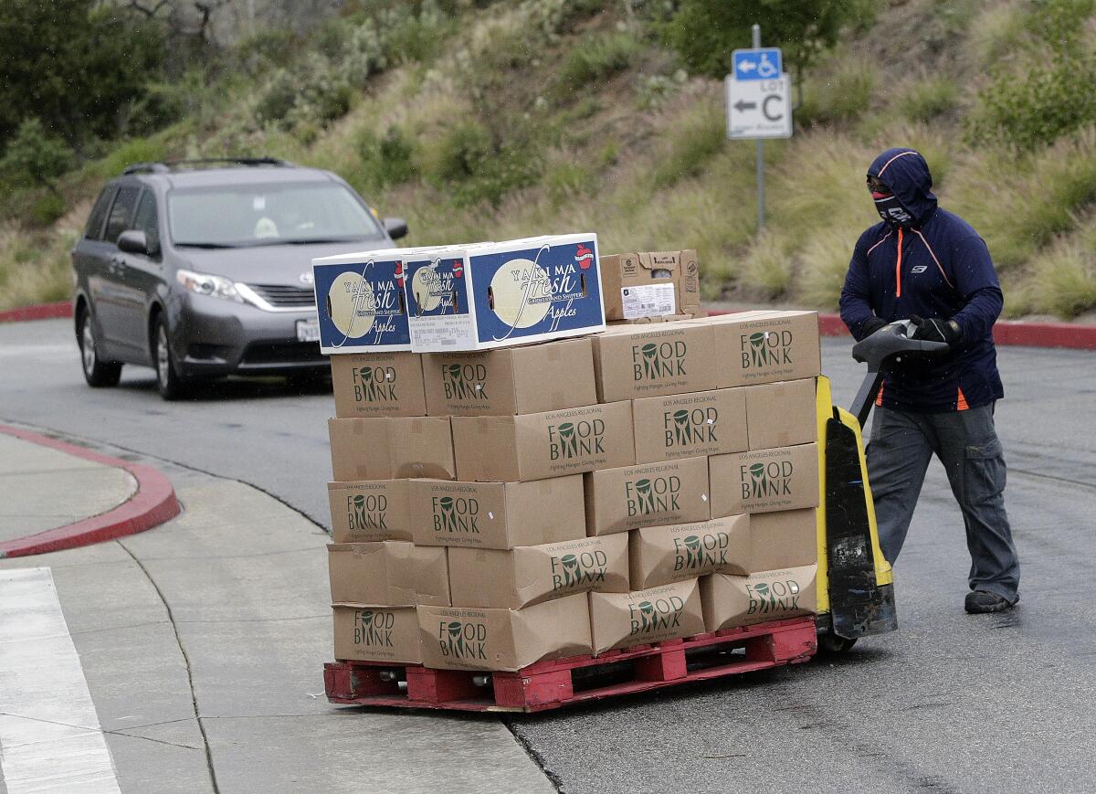 A pallet of canned food from the Food Bank is moved to a lower level of the GCC parking ramp on Tuesday, April 7, 2020.