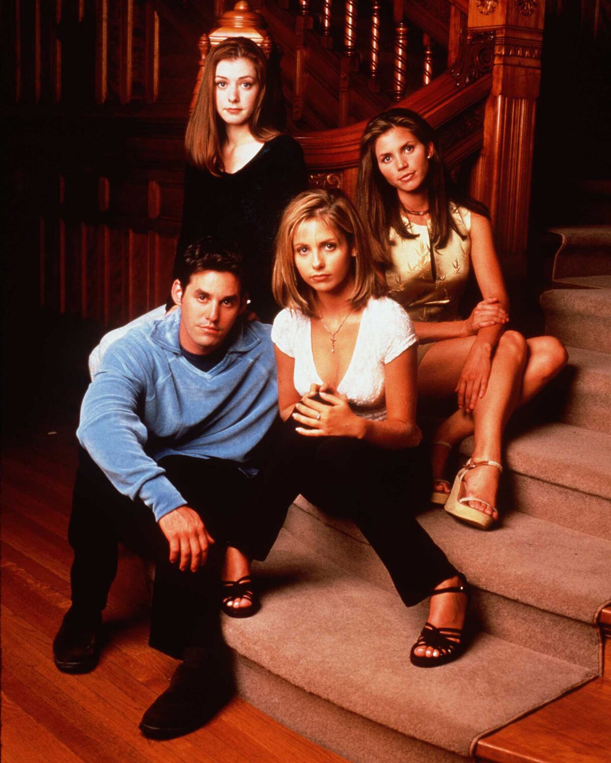 Four cast members of 'Buffy the Vampire Slayer' pose at the foot of a staircase