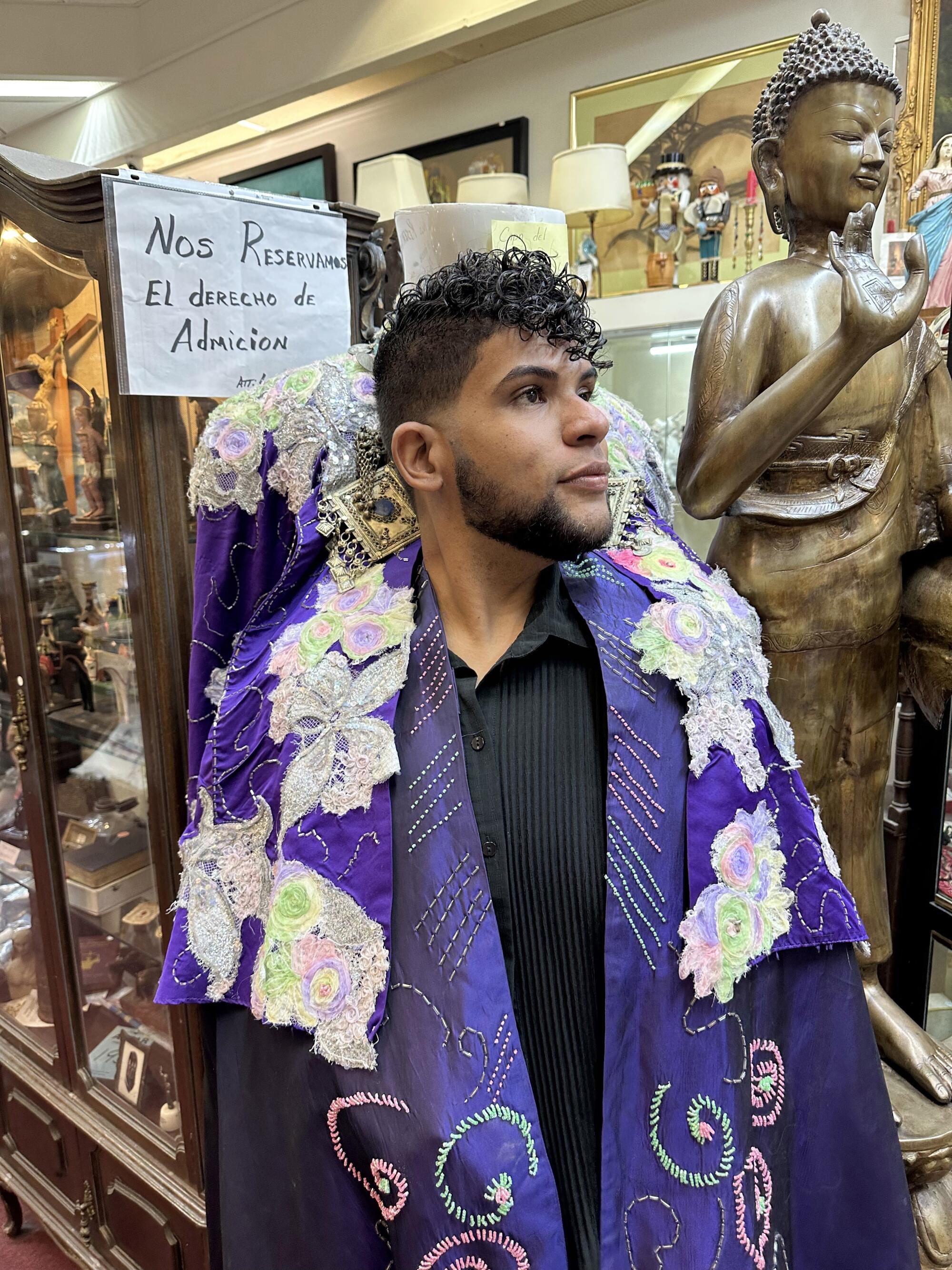 A man tries on a cape in a shop.