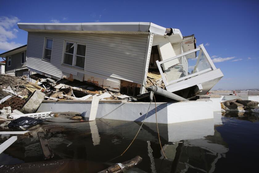 FILE - In this Thursday, Jan. 31, 2013 file photo, a storm-damaged beachfront house is reflected in a pool of water in the Far Rockaways, in the Queens borough of New York. A study released in the journal Nature Communications on Tuesday, May 18, 2021, says climate change added $8 billion to the massive costs of 2012's Superstorm Sandy. (AP Photo/Mark Lennihan, File)
