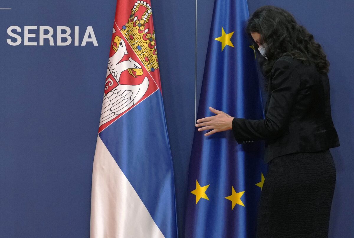 FILE - A protocol staff member adjusts a EU flag next to a Serbian flag, prior to the press conference of Montenegro's Prime Minister Zdravko Krivokapic and his Serbian counterpart Ana Brnabic at the Serbia Palace in Belgrade, Serbia, Wednesday, Nov. 3, 2021. Serbia is taking a significant step toward joining the European Union. Belgrade opened talks Tuesday, Dec. 14, 2021 on a series of policies linked to the environment but it was warned that progress on its European path still depends on normalizing relations with its former territory, Kosovo. Countries wanting to join the 27-country EU must bring their laws into line with the bloc’s standards. (AP Photo/Darko Vojinovic, File)
