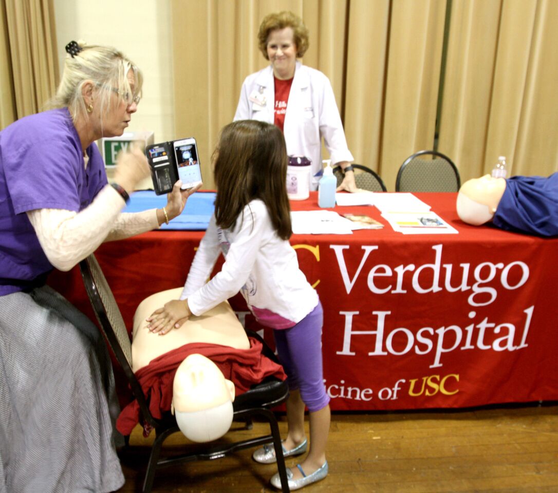Obstetrics consultant Jennifer Merkel, left, shows six-year old Nicole Assaturi of Glendale how to perform hands-only CPS at the Sixth Annual Glendale Health Festival at the Glendale Civic Auditorium in Glendale on Saturday, November 7, 2015.