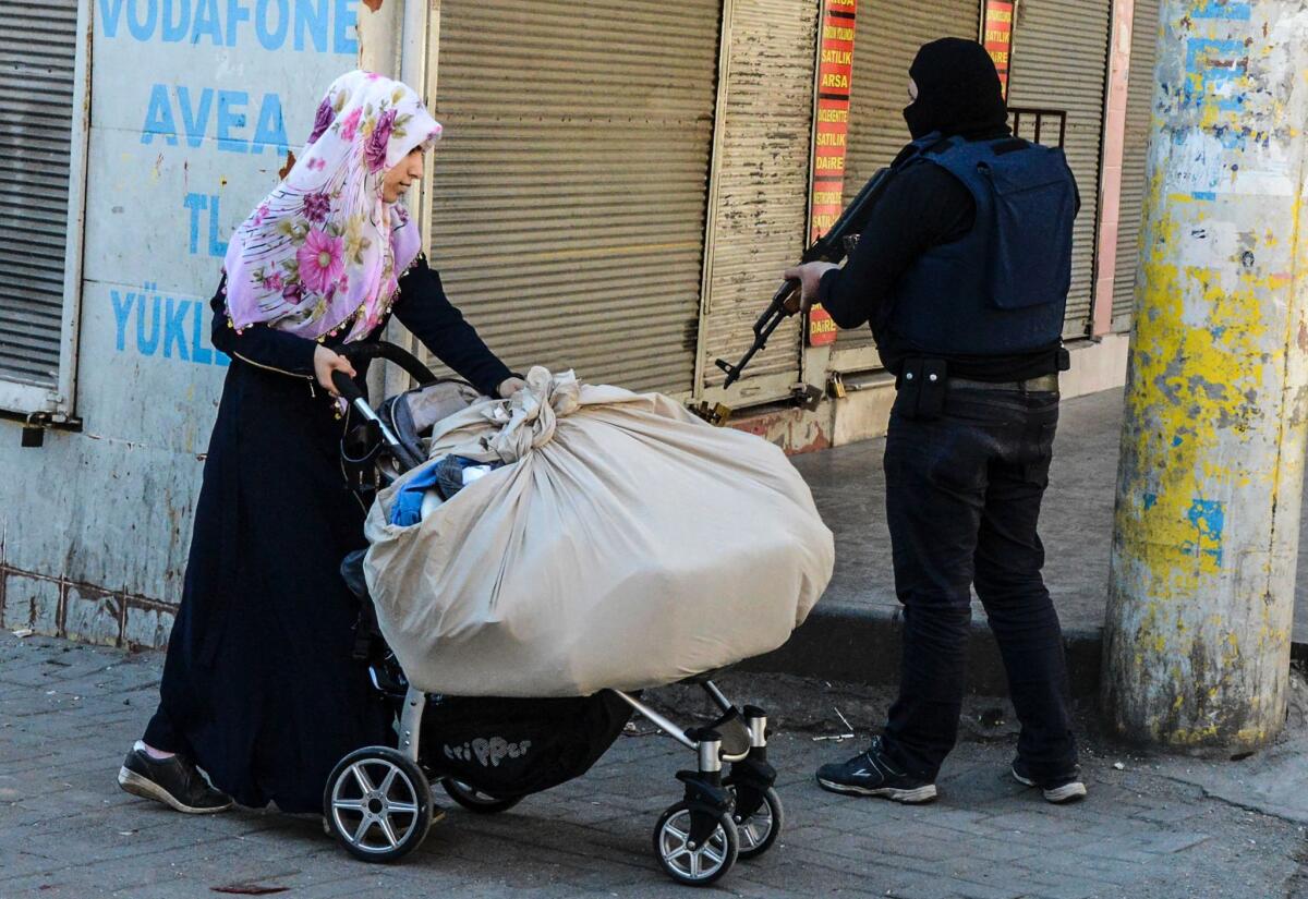 A woman passes a government soldier during clashes in central Diyarbakir, Turkey, on March 17.