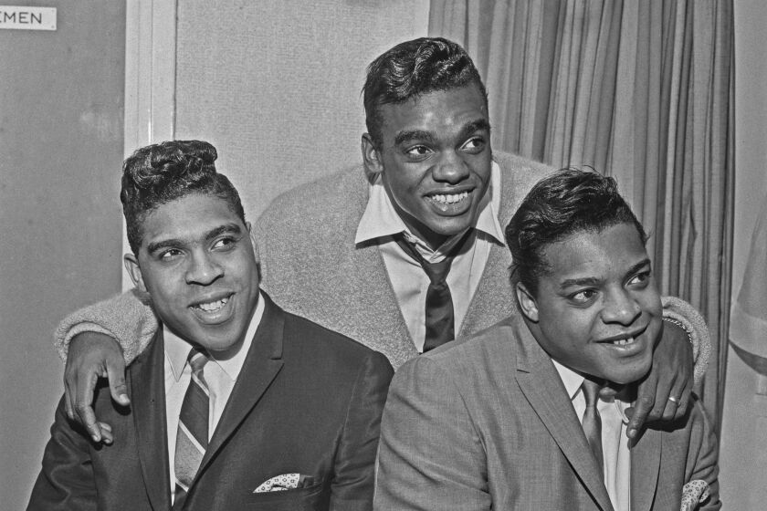 A black-and-white photo of three men smiling in suits
