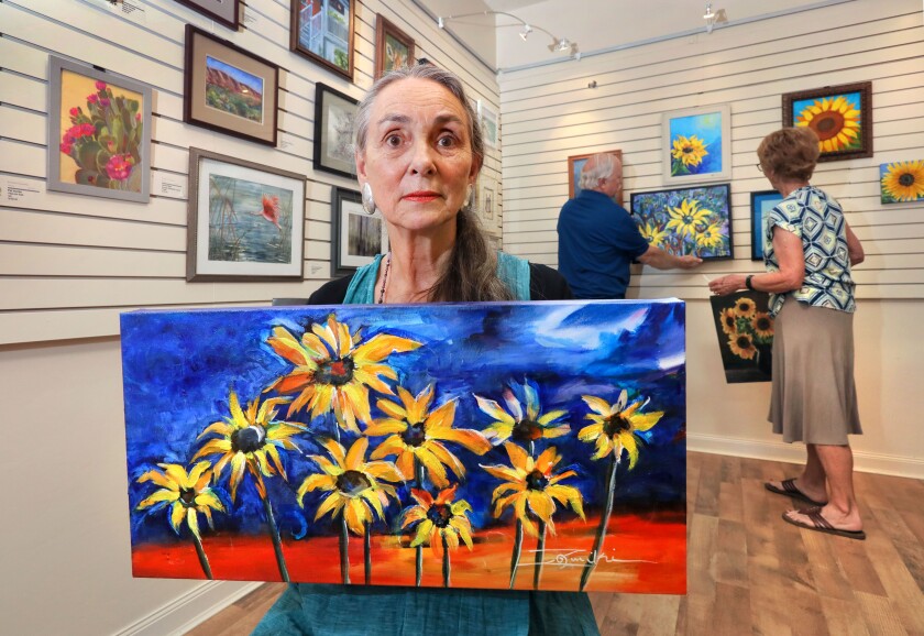 Artist Suzanne Nicolaisen holds a painting she created the exhibition "Sunflower for Ukraine."