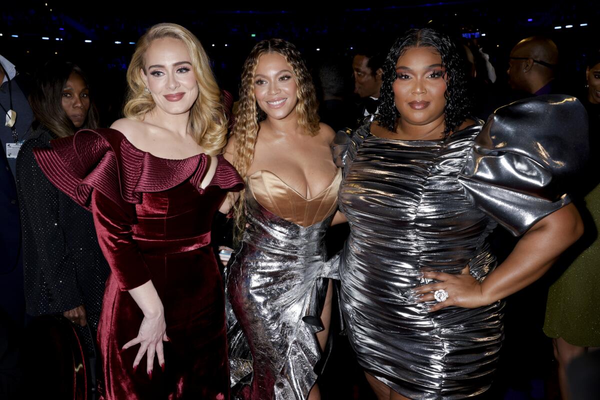 Three female artists in gowns at an awards show