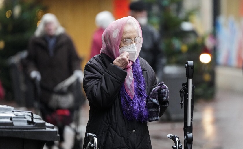A woman prepares her face mask due to the coronavirus pandemic in Gelsenkirchen, Germany, Monday, Nov. 29, 2021. (AP Photo/Martin Meissner)