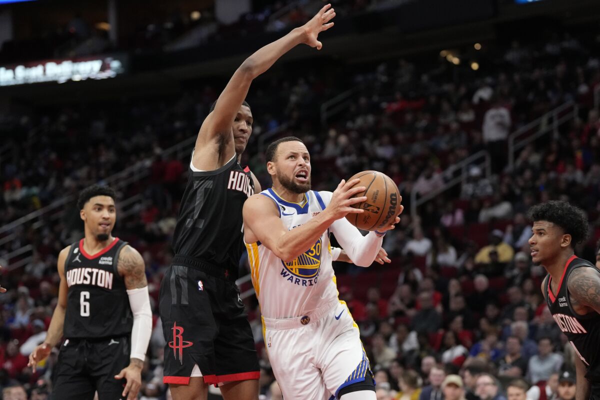 Golden State Warriors' Stephen Curry (30) drives to the basket as Houston Rockets' Jabari Smith Jr. defends during the second half of an NBA basketball game Monday, March 20, 2023, in Houston. The Warriors won 121-108. (AP Photo/David J. Phillip)