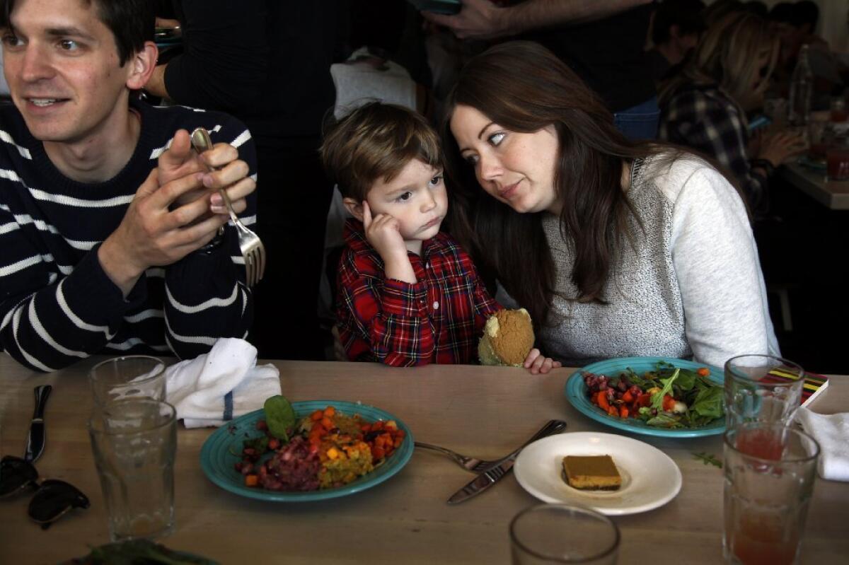 Three-year-old Henry Bradshaw talks with his mom, Lauren, at Cafe Gratitude's free vegan Thanksgiving feast. His dad, Joseph, is at left.