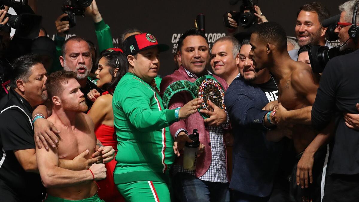Canelo Alvarez and Daniel Jacobs get into a shoving match as Golden Boy Promoter Oscar De La Hoya (with belt) intervenes during their weigh-in at T-Mobile Arena on Friday in Las Vegas.