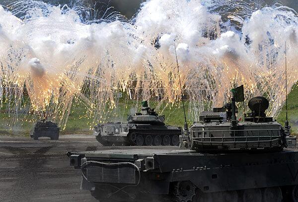 Japanese tanks spew umbrellas of gunfire during a public military exercise at the foot of Mt. Fuji. The annual drill attracts about 30,000 spectators.
