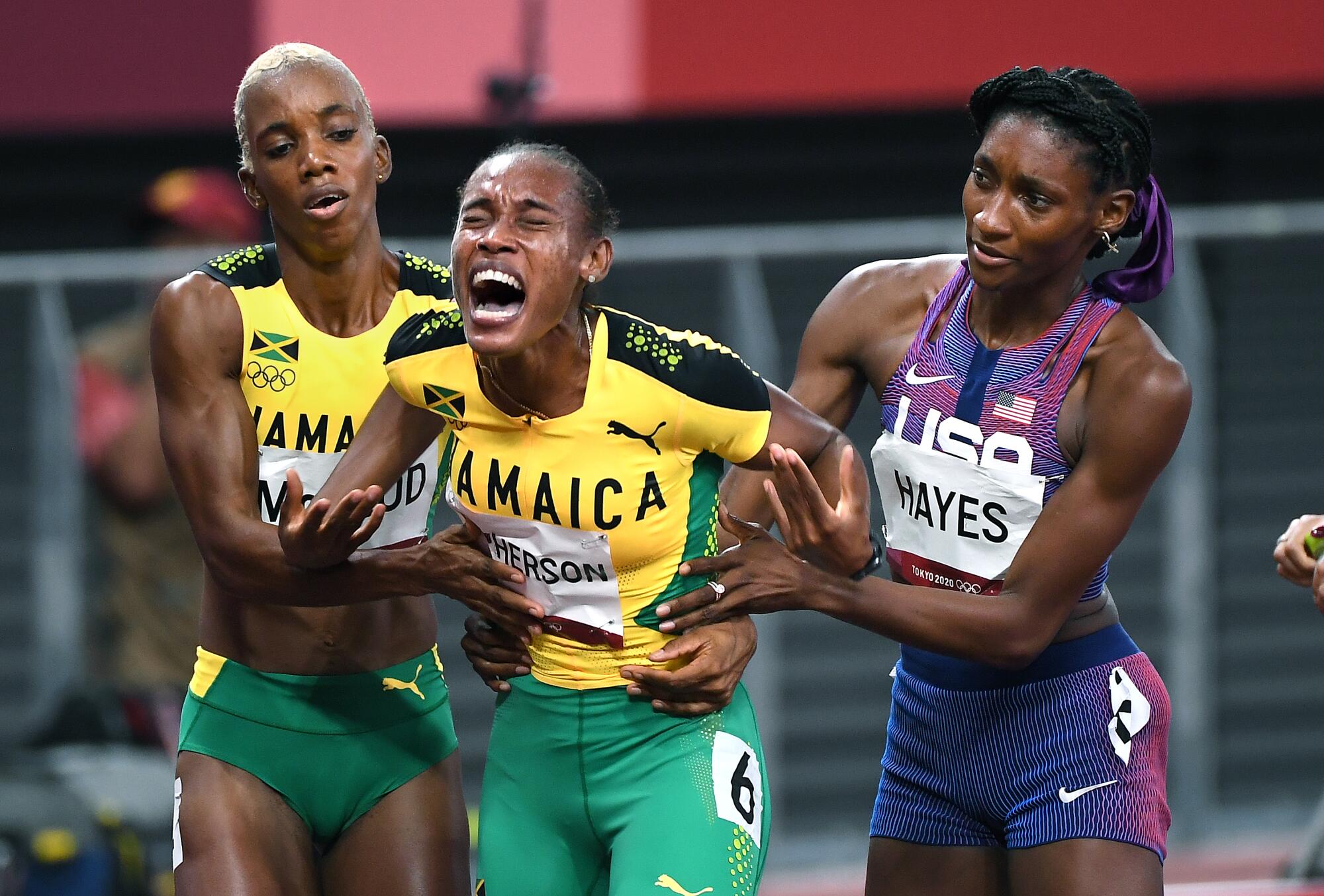 Stephanie McPherson cries out in pain as she is helped by Candice McLeod and Quanera Hayes after the 400 meters.