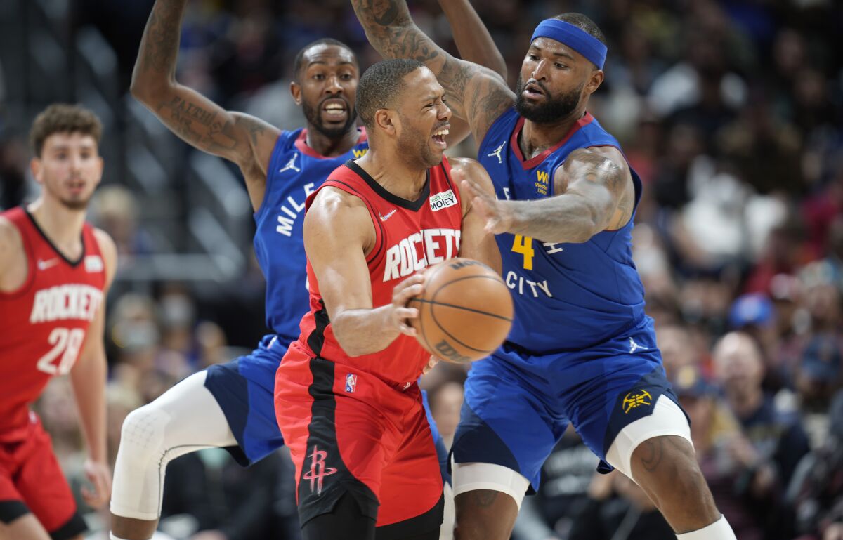 Houston Rockets guard Eric Gordon, center, passes the ball under pressure from Denver Nuggets guard Davon Reed, left, and center DeMarcus Cousins in the second half of an NBA basketball game Friday, March 4, 2022, in Denver. The Nuggets won 116-101. (AP Photo/David Zalubowski)