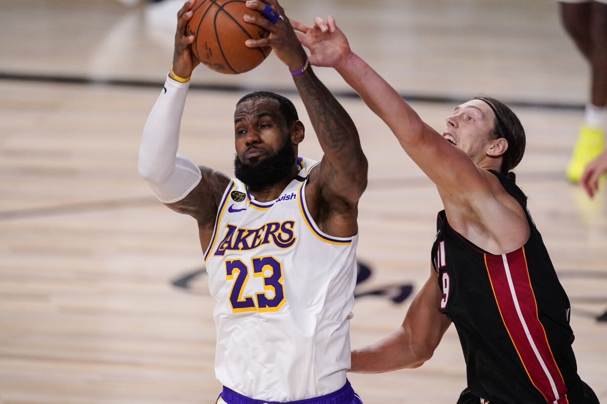 The Lakers' LeBron James and the Miami Heat's Kelly Olynyk fight for control for the ball.