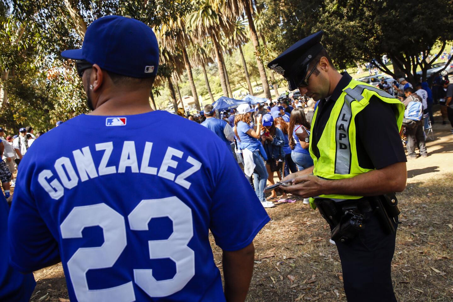 An LAPD officer writes a ticket for alcohol as Dodgers fans tailgate before Monday's opening day in Elysian Park despite new parking restrictions and police enforcement.