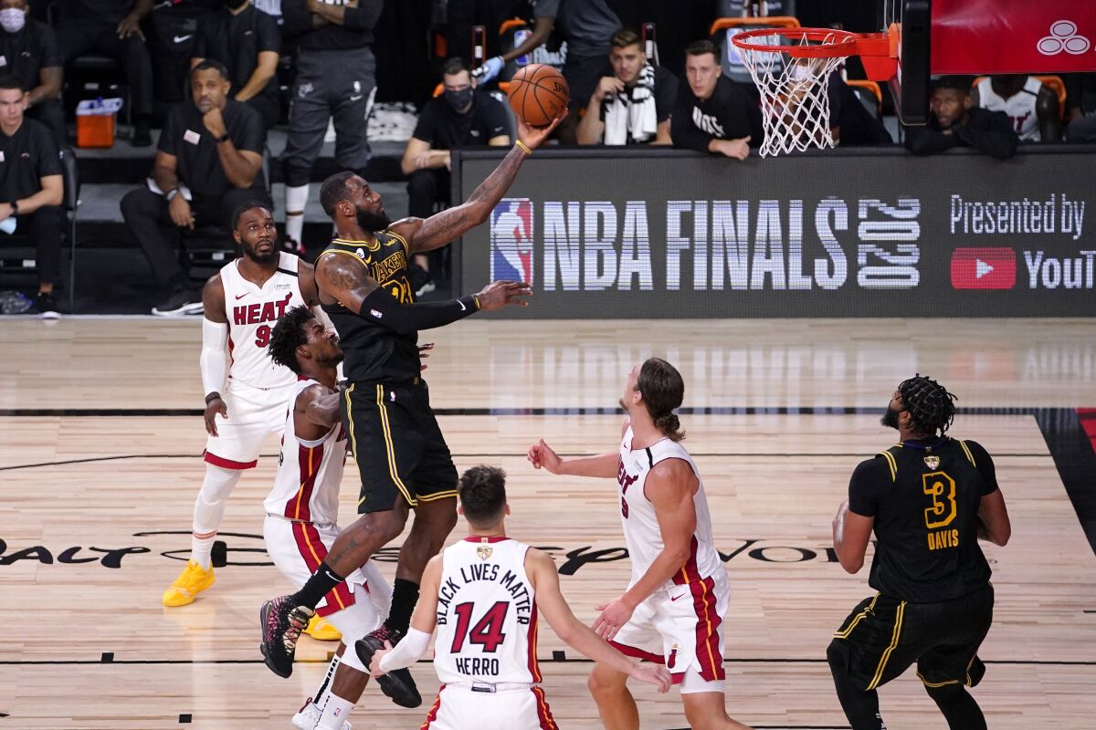 Los Angeles Lakers forward LeBron James (23) goes up for a shot between Miami Heat's Jimmy Butler, center left, Tyler Herro (14), and Kelly Olynyk (9) during the second half of Game 2 of basketball's NBA Finals, Friday, Oct. 2, 2020, in Lake Buena Vista, Fla. (AP Photo/Mark J. Terrill)