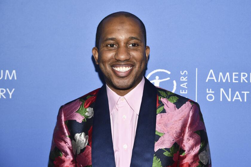 A man smiling in a floral suit against a blue background