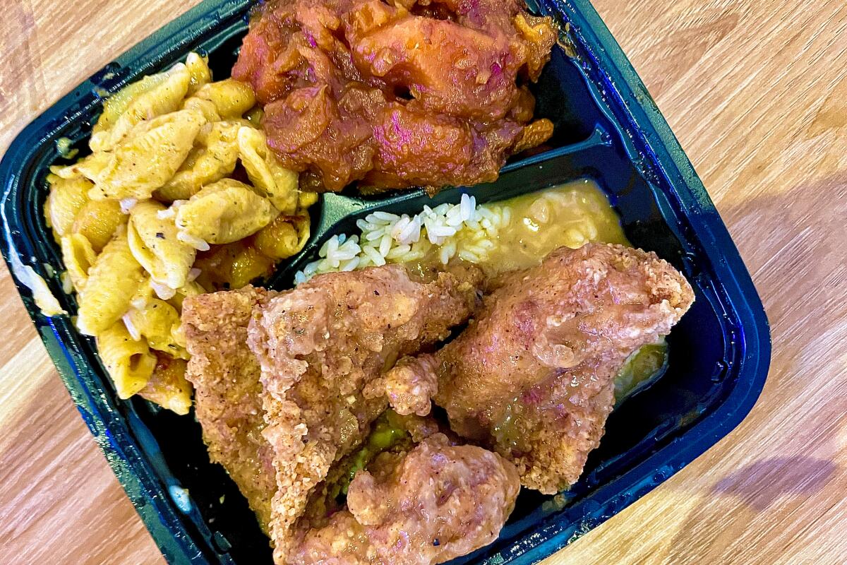 Turkey chops with rice and gravy, macaroni and cheese and candied yams in a styrofoam takeout container