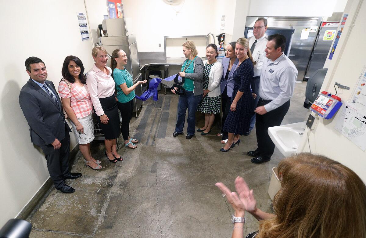 Glendale Unified School District members, Benjamin Franklin Elementary's Foundation Green Team, Franklin Elementary administration, and Hobart Corp. representatives pose for a ribbon-cutting inside the washing area with a new dishwasher and counter at a ceremony recognizing a conservation initiative at Benjamin Franklin Elementary School on Monday. The Hobart Corp. donated a new dishwashing system, with a new energy-efficient dishwasher and lunch trays to reduce the amount of waste generated from the school-lunch program.