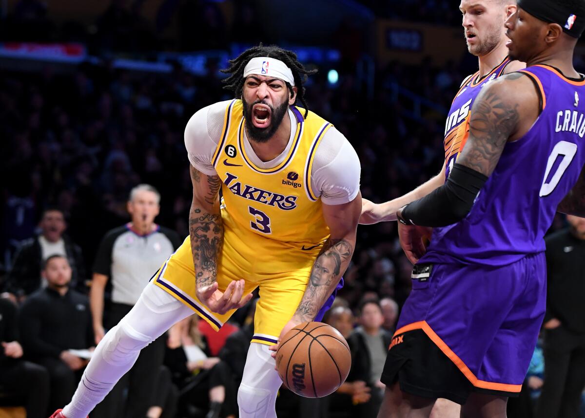 Lakers Anthony Davis lets out a yell as he celebrates a dunk in front of Suns Torrey Craig (0) and Jock Landale