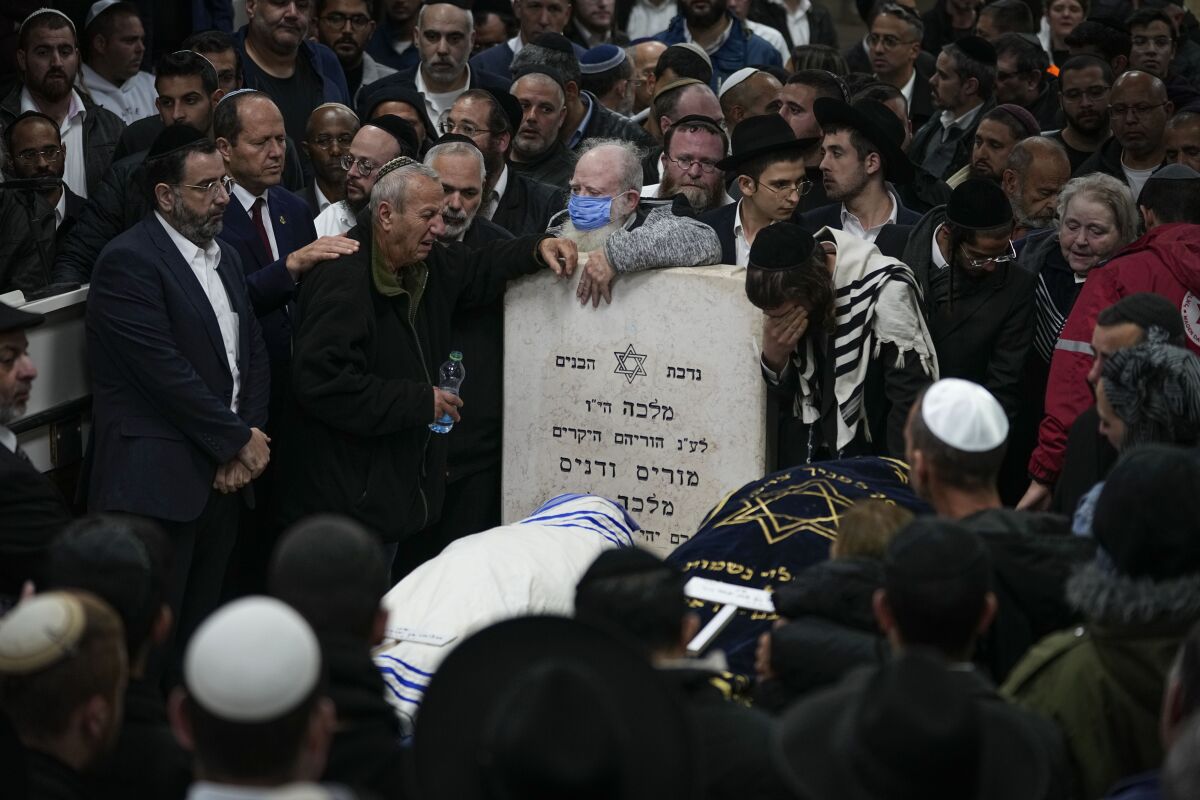 Mourners attend the funeral of Israeli couple Eli Mizrahi and his wife, Natalie, victims of a shooting attack Friday in east Jerusalem, at the cemetery in Beit Shemesh, Israel, early Sunday, Jan. 29, 2023. On Friday a Palestinian gunman opened fire outside an east Jerusalem synagogue, killing the couple and another five people, including a 70-year-old woman, and wounding three others before he was shot and killed by police, officials say. It was the deadliest attack on Israelis since 2008 and raised the likelihood of more bloodshed. (AP Photo/Ariel Schalit)