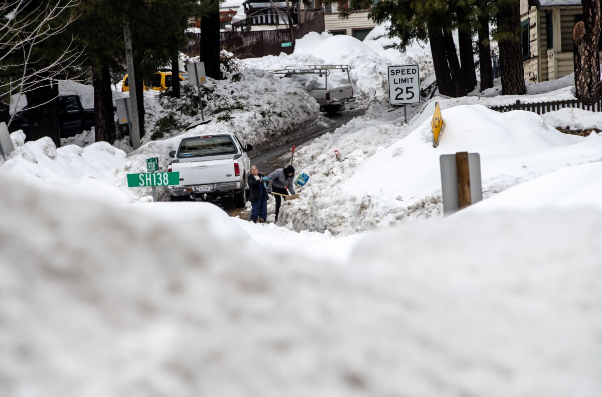 Deanna Beaudoin helps a neighbor shovel a shared driveway on March 6 in Crestline.