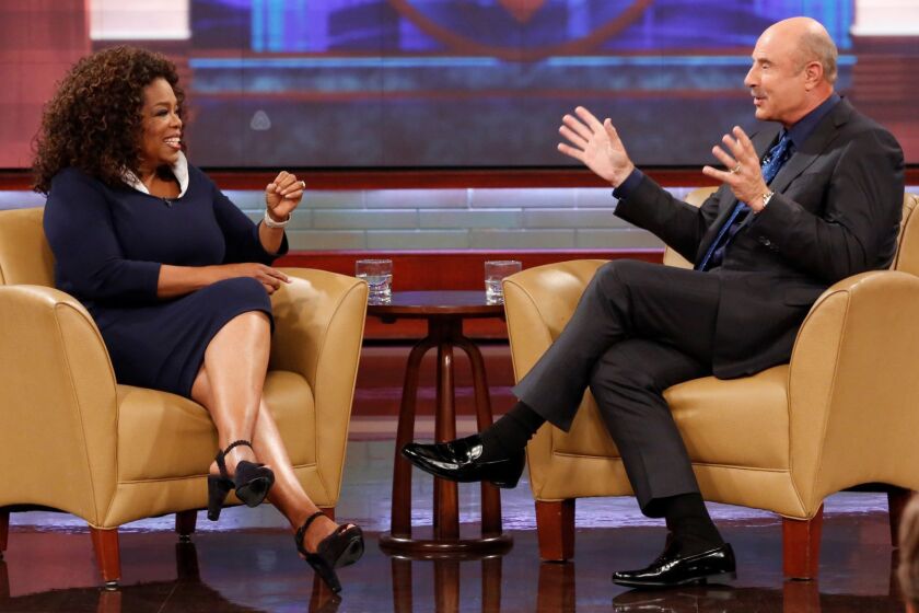 This Sept. 22, 2015 image released by CBS Media Ventures shows Oprah Winfrey, left, and Dr. Phil McGraw on the set of the "Dr. Phil." McGraw says he'll stop making new episodes of his daytime TV show after 21 years this spring. The Texas psychologist emerged from Oprah Winfrey's TV tree, spinning off his frequent appearances there to start his own show in 2002. (Robert Voets/CBS Media Ventures via AP)