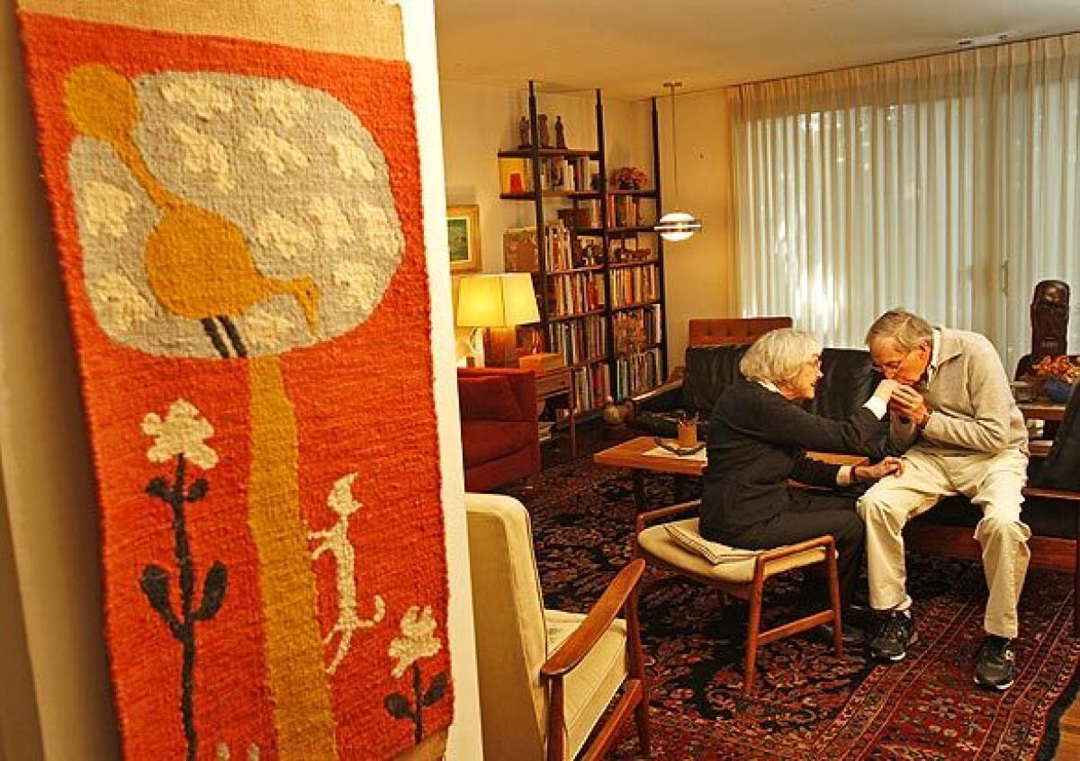 Though little known to most of the public, Evelyn and Jerome Ackerman are revered in design circles for ceramics, tile mosaics, woodcarvings and textiles that had the kind of cheap-chic ethos so popular today. "One of our goals was to be affordable," Evelyn Ackerman says. "Not having a lot of money was the position we were in most of our young life, so it is what we strove to do for others." The Ackermans invited the Home section for a peek inside their home and studio. Here, with her "Cat and Bird" tapestry hanging by the living room, Evelyn Ackerman gets a little love from husband Jerome.
