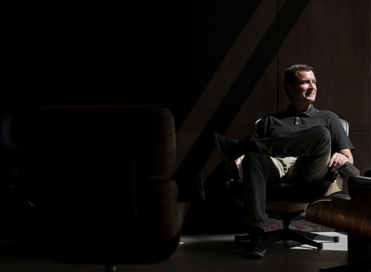 A portrait of Mike Ybarra in a beam of light in a dark room.