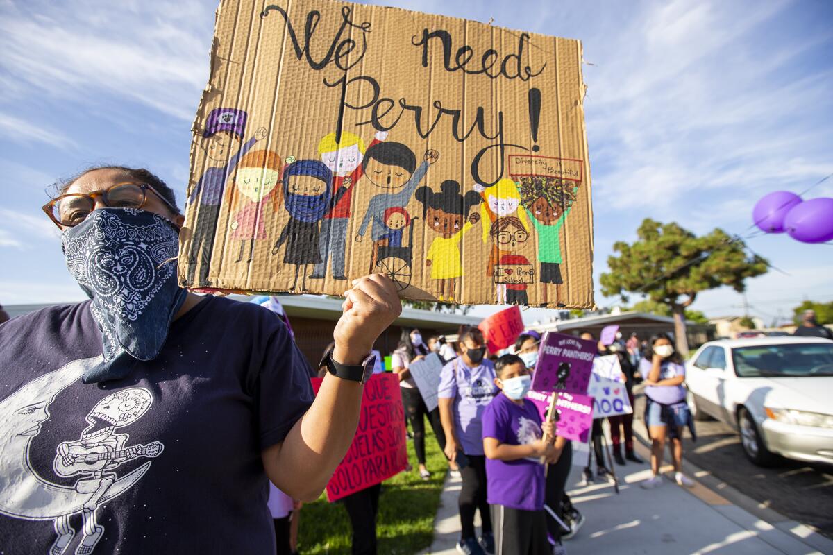 Diane Parras, an alumna of Perry Elementary School, holds a sign during a protest of the school's closure on Tuesday.