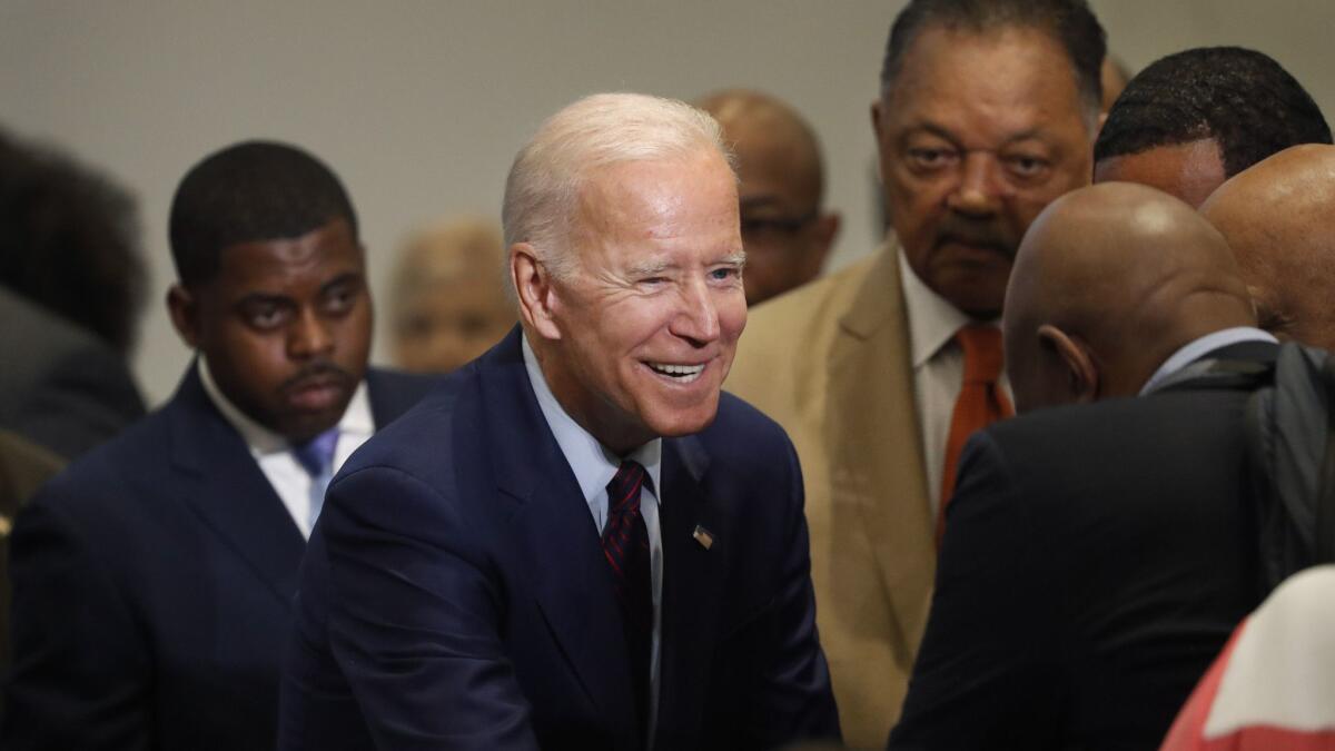Former Vice President Joe Biden greets audience members with the Rev. Jesse Jackson, center right, before addressing the Rainbow PUSH Coalition convention Friday in Chicago.