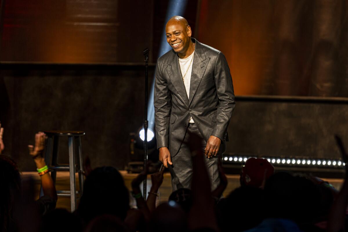 A man standing on a stage in a black, leather suit.