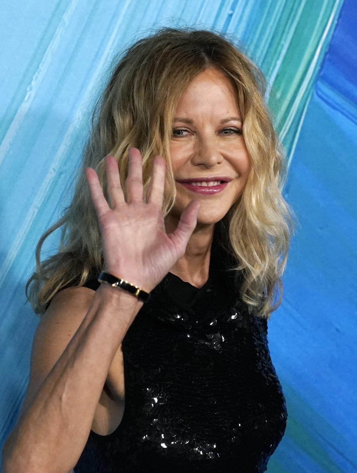 Meg Ryan waving and smiling while wearing black sequin dress at red carpet event