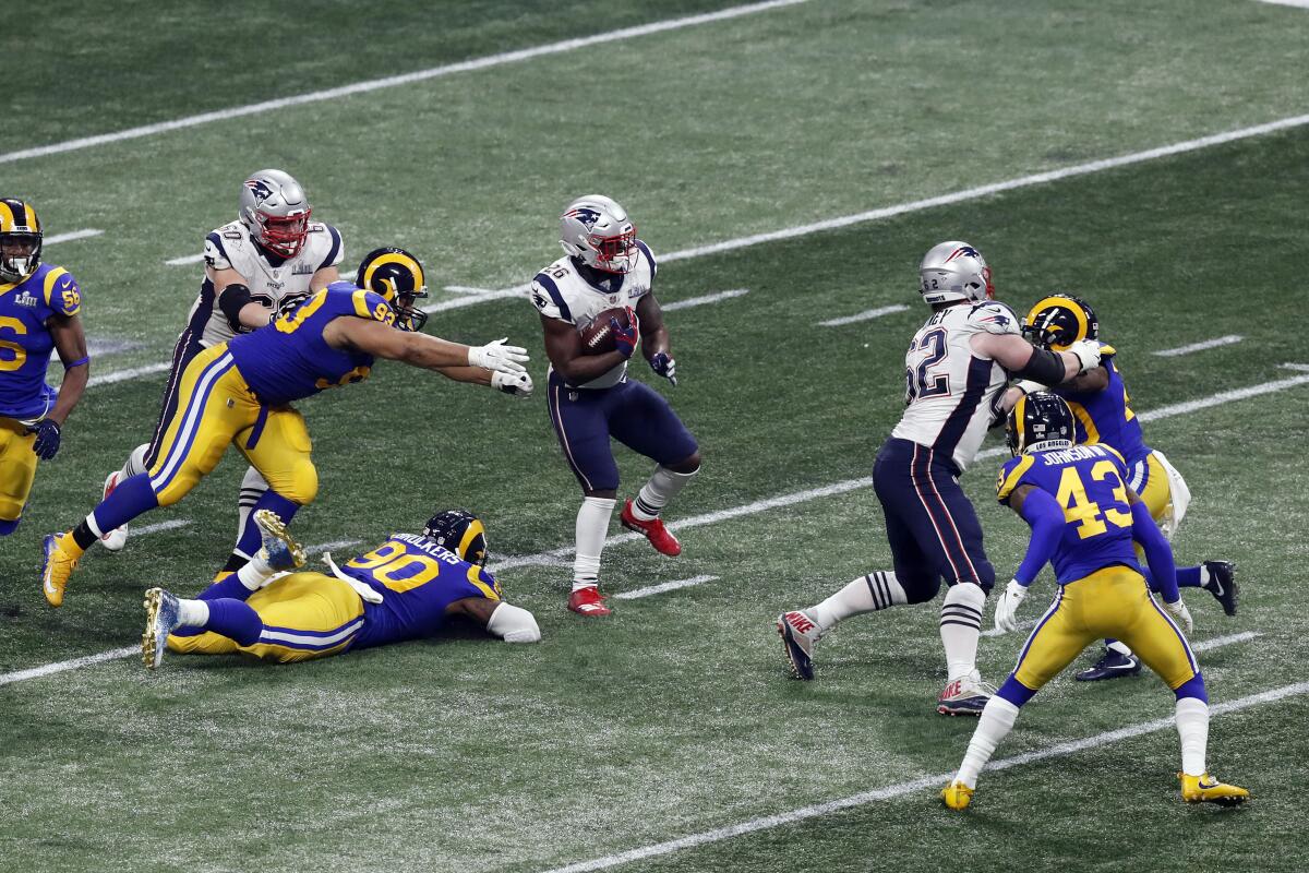 Patriots tailback Sony Michel runs past Rams Ndamukong Suh and Michael Brockers during Super Bowl 53 