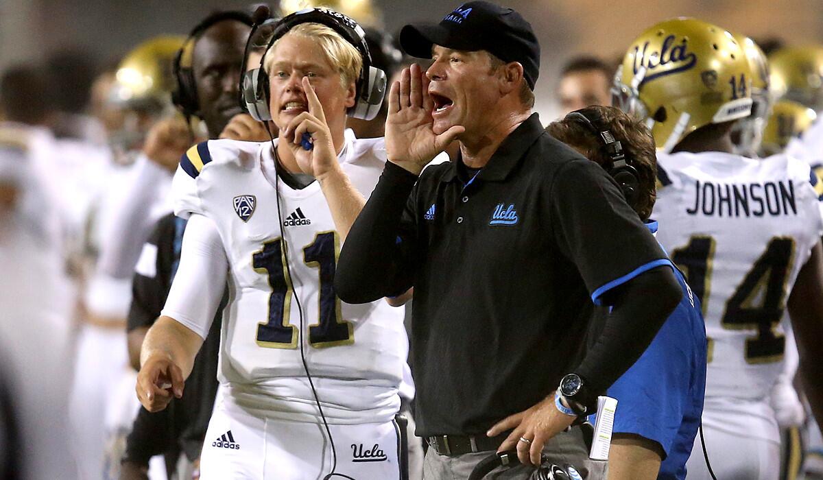 UCLA Coach Jim Mora and backup quarterback Jerry Neuheisel (11) relay plays to the offense during their game against Arizona State on Thursday night.