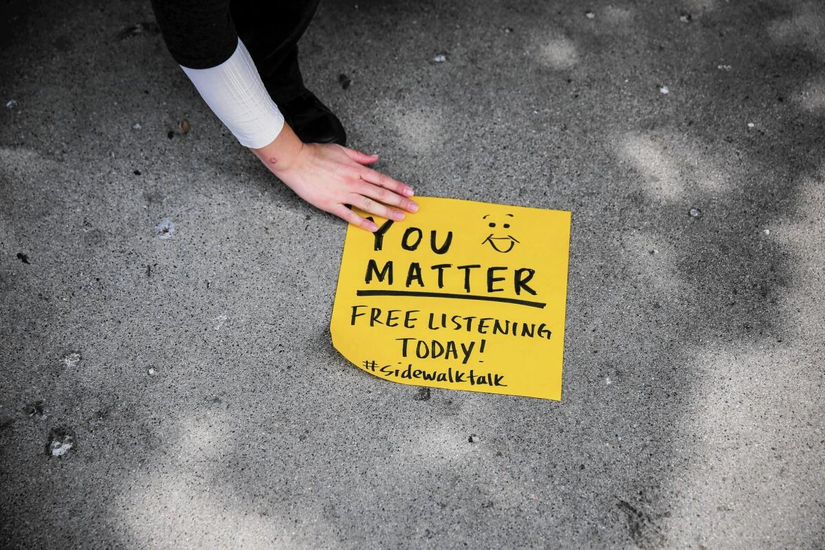 Mary Clark, a volunteer with L.A.'s Sidewalk Talk, works to secure a handmade sign offering "Free Listening" at the North Hollywood Metro Station.