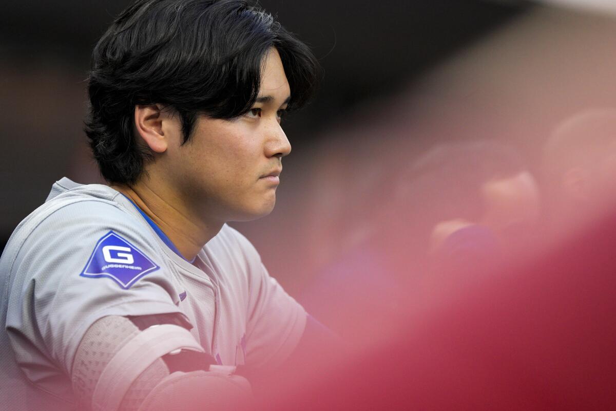 Shohei Ohtani stands in the dugout.