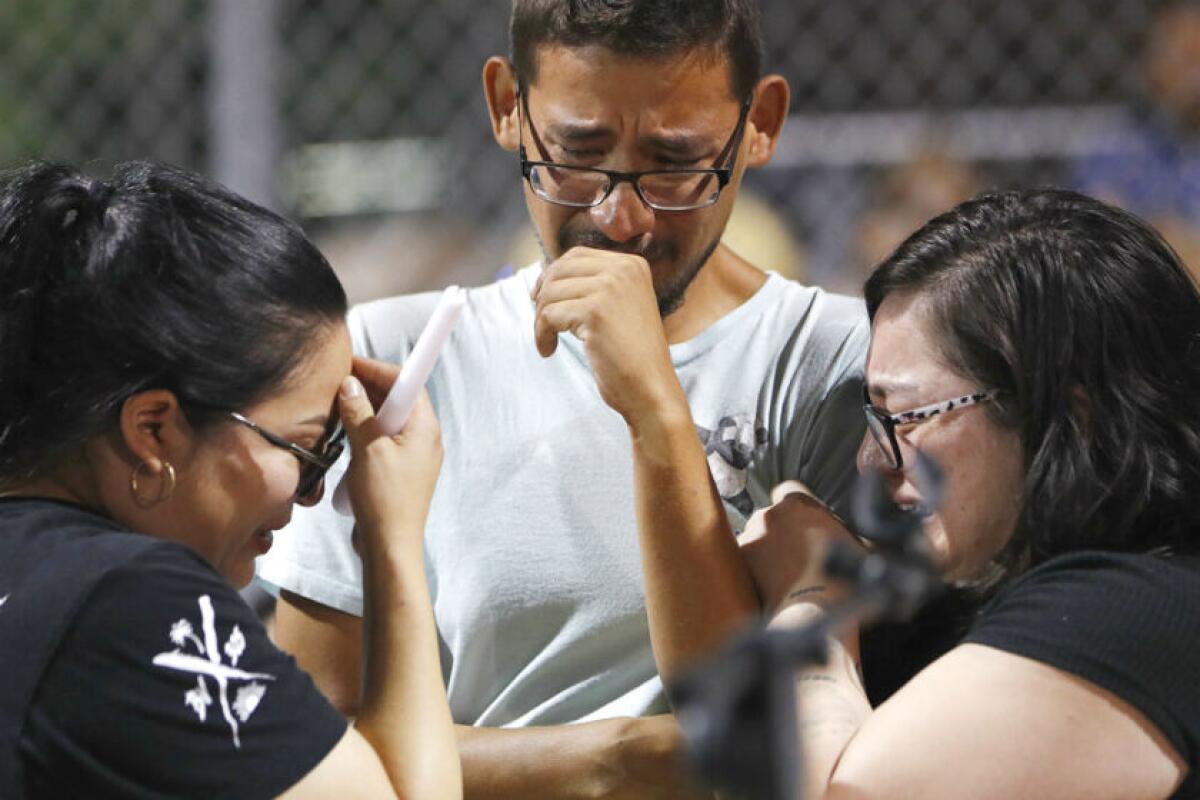 People are overcome during a vigil for victims of Saturday's mass shooting in El Paso.