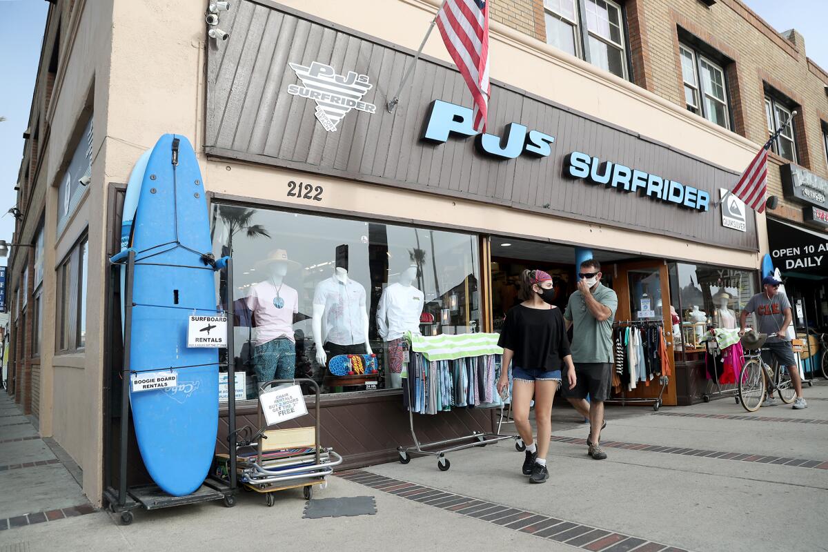 Customers wearing face masks walk out of the PJ's Surfrider sportswear store near the Newport Beach Pier on Tuesday.