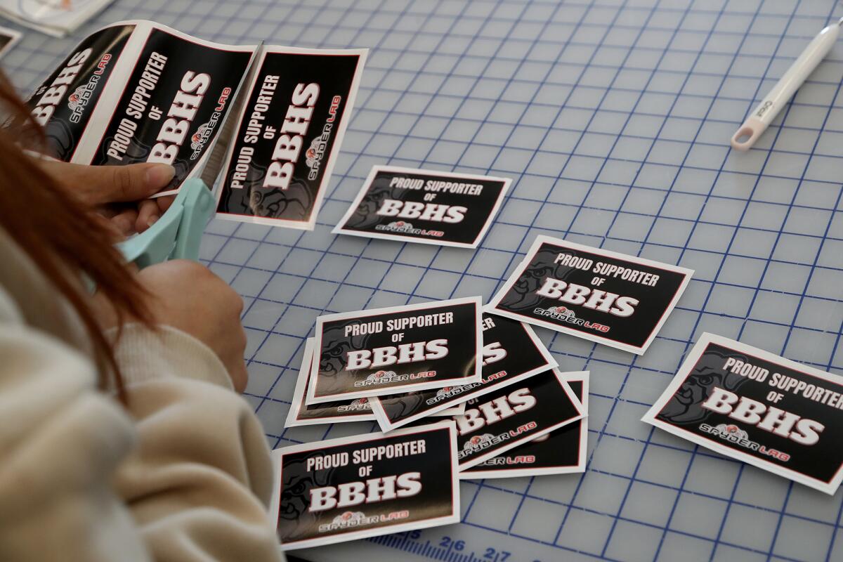 A student prepares 'Proud supporter of BBHS Spyder Lab' stickers during an open house.