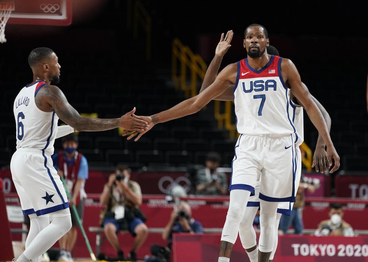 Kevin Durant and Damian Lillard high-five on the basketball court at the Tokyo Olympics.