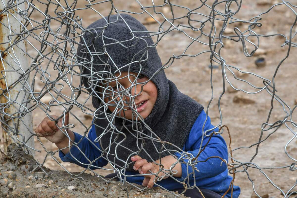 A child sits behind a wire fence in Al Hol camp, which houses relatives of Islamic State members, in Hasakah governorate in northeastern Syria.